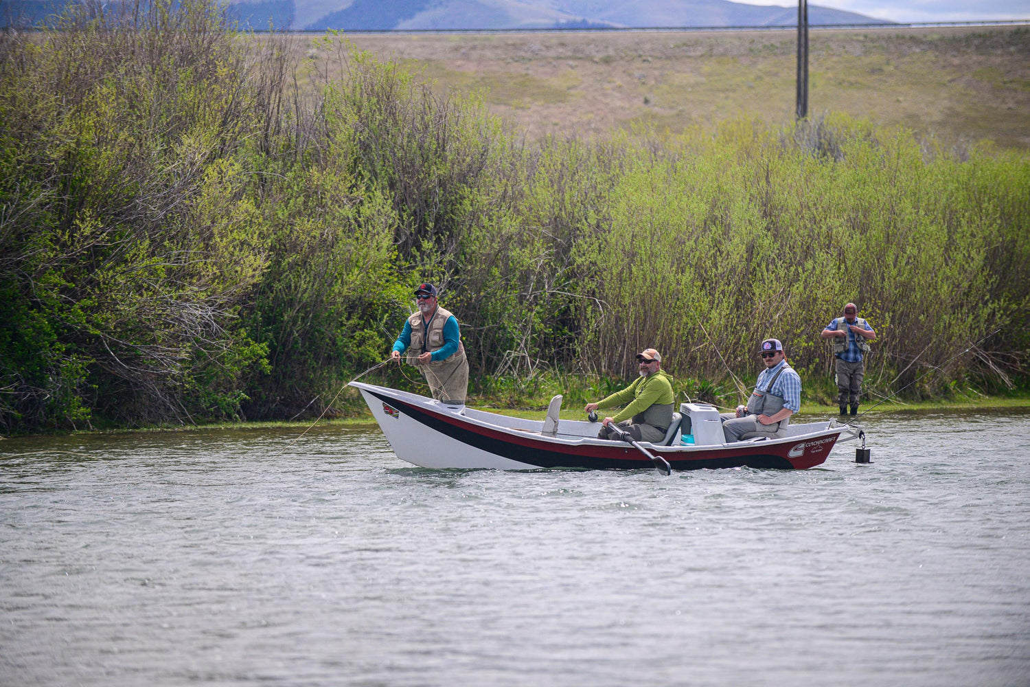 Three people in a drift boat fly fishing