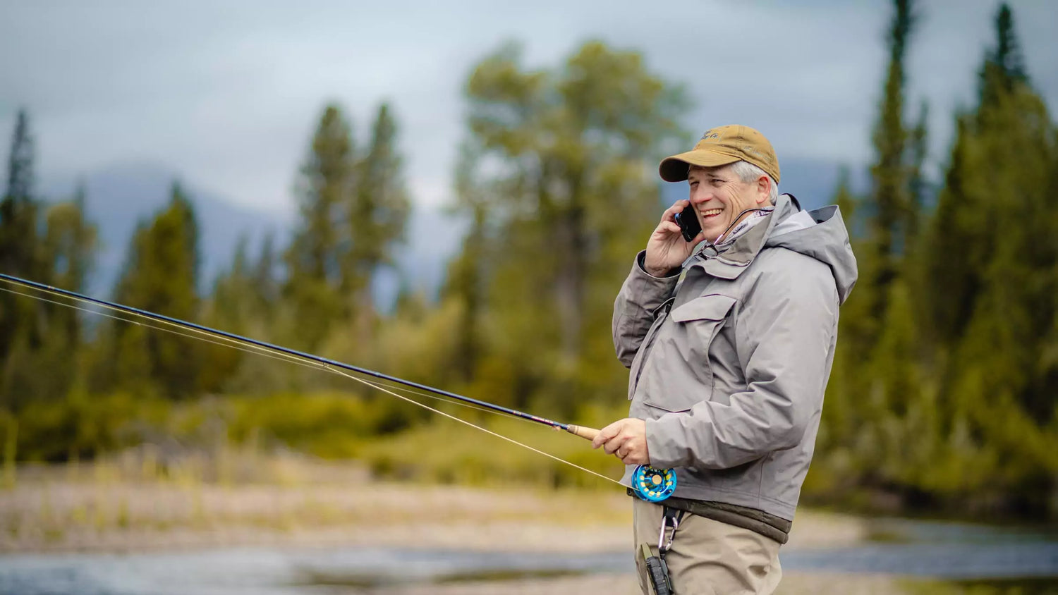 Man Holding Fly Rod Talking with Affiliate on Phone