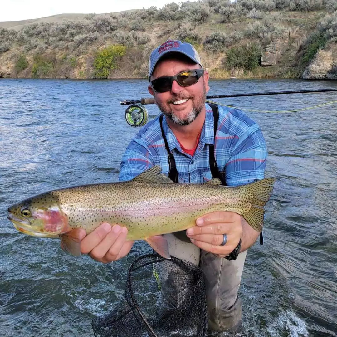Man with Fly Rod Across Shoulders Holding up a Rainbow Trout