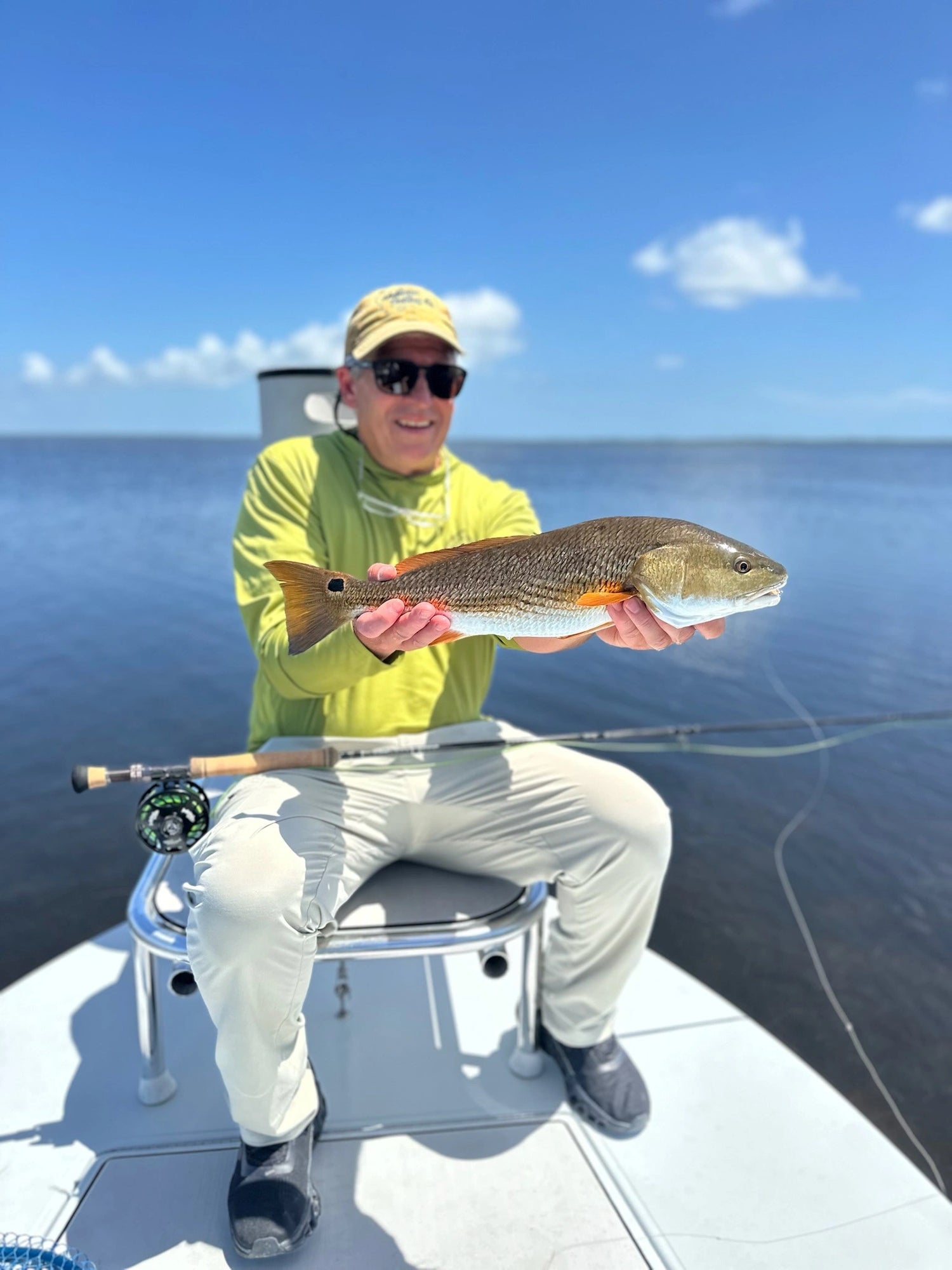 Fly Fisherman on a Boat Holding a Redfish