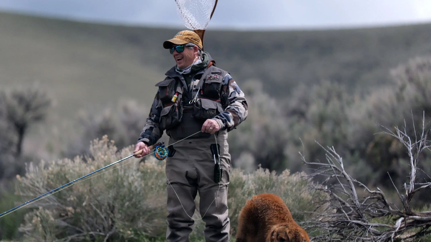 Fly fisherman laughs while stripping line from his fly fishing rod. 